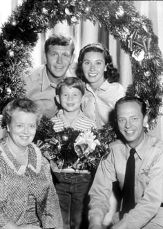 an old black and white photo of a family with christmas wreaths on their heads