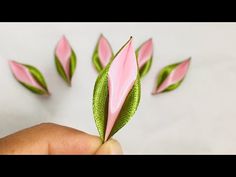 a hand holding a pink flower with green leaves