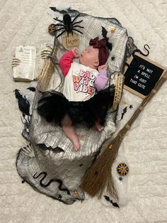 a baby dressed up as a witch laying on top of a bed with halloween decorations