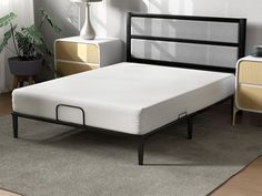 a bed with a white mattress and black frame in a room next to two nightstands