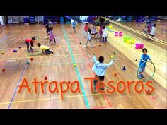 a group of people playing with tennis balls and racquets on an indoor court