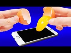 two hands are holding an orange and yellow object over a cell phone that is being held by one hand