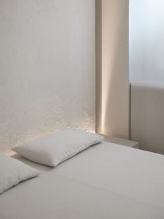 a white bed with two pillows on top of it