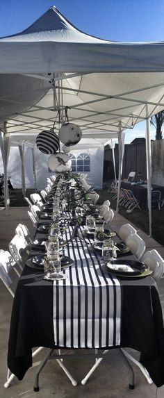 a long table with black and white cloths under a tent