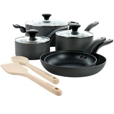 an assortment of black pots and pans with wooden utensils on a white background