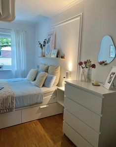 a bedroom with a bed, dresser and large mirror in it's center area