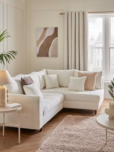 a living room filled with white furniture and lots of pillows on top of it's couches