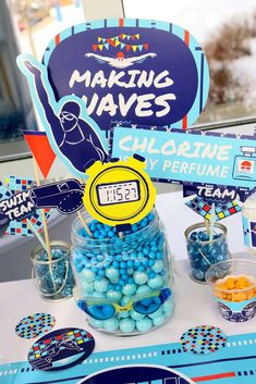 a table topped with blue and yellow candies next to a sign that says making waves