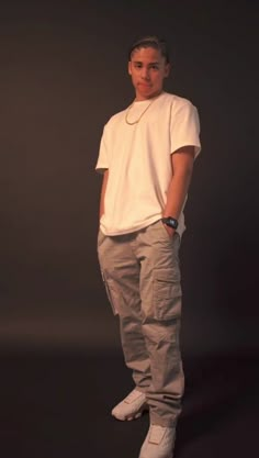 a man standing in front of a black background with his hands in his pockets and looking at the camera