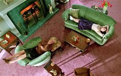 two women laying on green couches in a living room