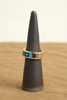 a ring that is sitting on top of a wooden stand with a black cone in the background