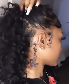 a woman with tattoos on her neck and behind her ear is combing her hair