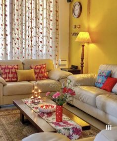 a living room with couches, tables and candles in the centerpieces on the coffee table