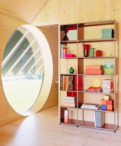 a book shelf with many books on it and a circular window in the back ground