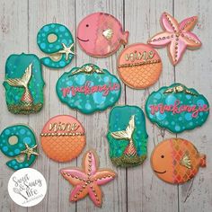 decorated cookies are arranged in the shape of mermaids and fish on a wooden table