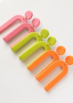 four pairs of neon colored hair clips on a white surface with clippings attached to them