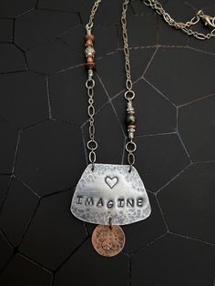 a necklace that says imagine with a penny hanging from it's center and the word imagine written on it