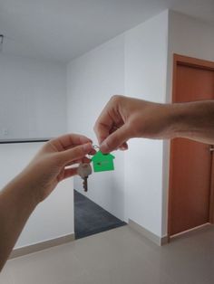 two people holding keys to each other in front of a house shaped keychain