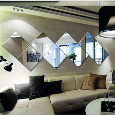 a living room filled with white furniture and lots of mirrors on the wall above it