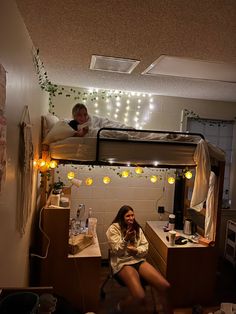 two women sitting on bunk beds in a room with string lights strung across the ceiling