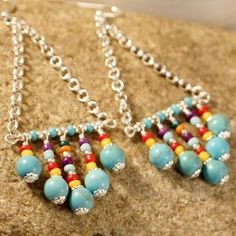 two pairs of colorful beaded earrings sitting on top of a rock