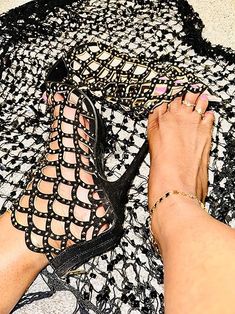 a woman's feet and black shoes are on a white lace tablecloth with crocheted design