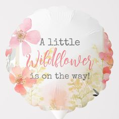 a white balloon with pink flowers and the words, little wildflower is on the way