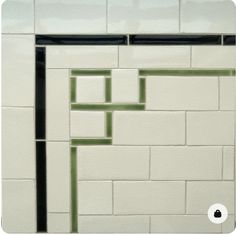 a white and green tiled wall with black trim