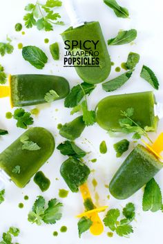 green popsicles with limes and mint leaves on a white surface surrounded by lemon wedges