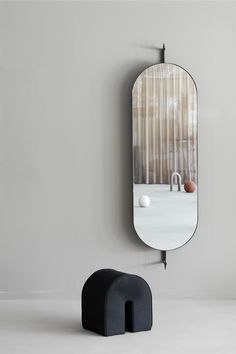 an oval mirror on the wall next to a black stool