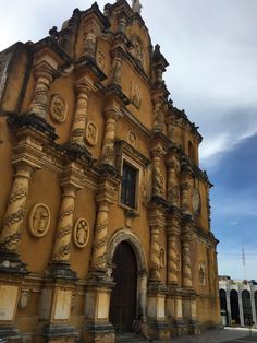 an old church with ornate carvings on the front and side walls, against a cloudy blue sky