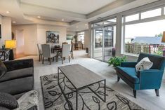 a living room filled with furniture next to a large glass doored kitchen and dining area