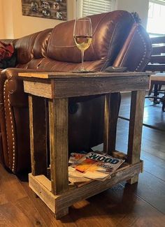 a glass of wine sitting on top of a wooden table next to a leather couch