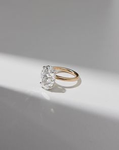 a close up of a diamond ring on a white surface with sunlight coming through the window