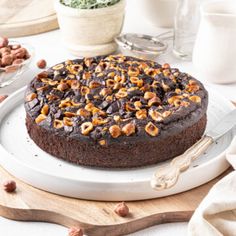 a chocolate cake on a white plate with nuts