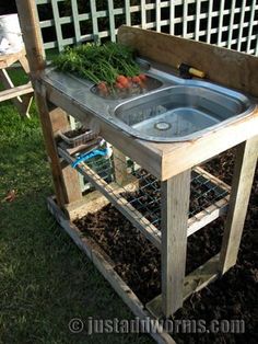 an outdoor sink in the middle of some grass and plants on it's stand