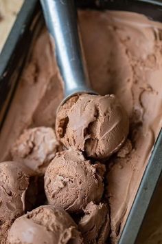 chocolate ice cream in a metal pan with a scoop resting on the top, ready to be eaten