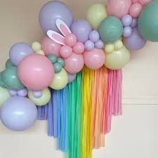 a bunch of balloons and streamers in the shape of a bunny on a rainbow colored wall