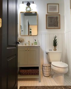 a white toilet sitting next to a sink in a bathroom under a mirror and lights