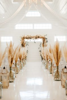 the aisle is decorated with tall grass and candles