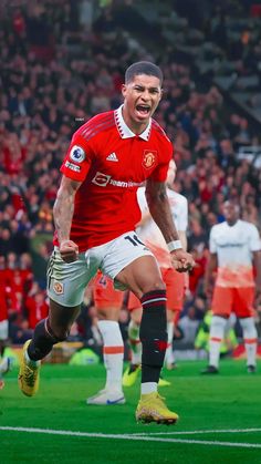 a soccer player is running on the field with his mouth open and hands in the air