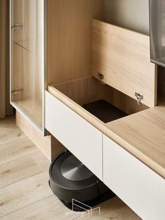 a roomba is sitting on the floor in front of a cabinet with its door open