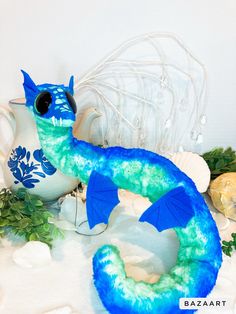 a blue and green dragon figurine sitting on top of a table next to other decorations