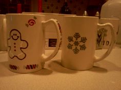 two coffee mugs sitting on top of a counter next to each other, decorated with gingerbread cookies and candy canes