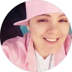 a woman wearing a pink hat and smiling at the camera in a circular photo with a chain around her neck