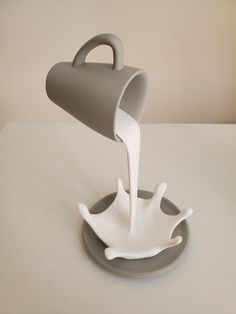 a gray and white coffee cup sitting on top of a saucer in the shape of a boat