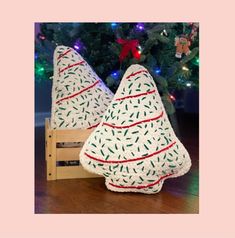 two knitted christmas trees sitting on top of a wooden crate next to a christmas tree