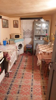 an old fashioned kitchen is shown in this image, with many appliances and table cloths on the floor