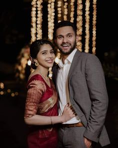 a man and woman standing next to each other in front of some strings of lights