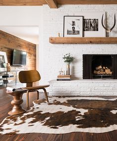 a living room with a cow hide rug on the floor and a white brick fireplace